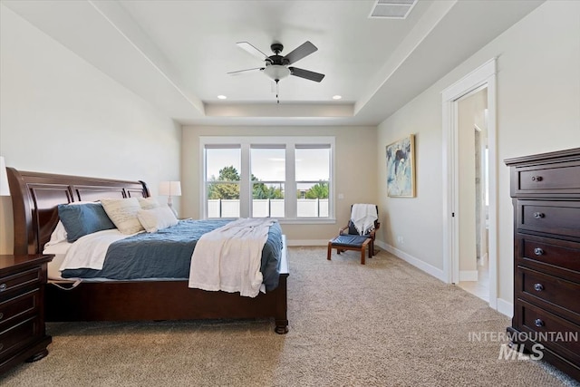 bedroom with a raised ceiling, light carpet, baseboards, and ceiling fan