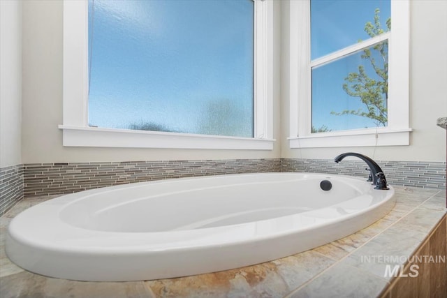 full bath with plenty of natural light and a garden tub