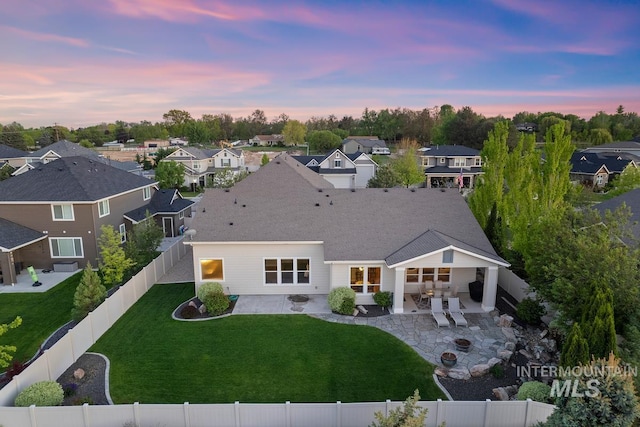 back of property at dusk with a patio area, a residential view, and a fire pit