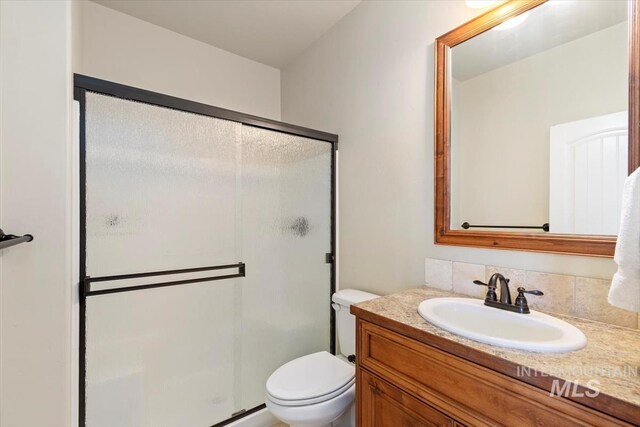 bathroom featuring a stall shower, vanity, and toilet