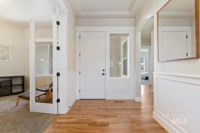 entrance foyer featuring light wood-style floors and arched walkways