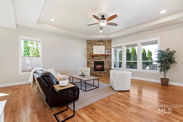 living area with a tray ceiling, plenty of natural light, a ceiling fan, light wood-style floors, and recessed lighting
