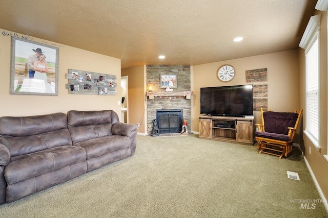 carpeted living room featuring a stone fireplace and a textured ceiling