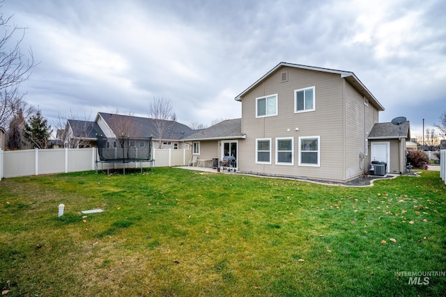 back of house with central air condition unit, a yard, a patio, and a trampoline