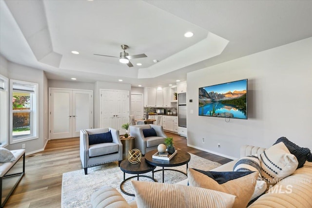 11298 W Charitan St, Boise, ID 83713 - living room with a tray ceiling, baseboards, recessed lighting, light wood-style flooring, and a ceiling fan