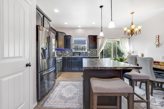 kitchen featuring a kitchen breakfast bar, tasteful backsplash, a kitchen island, appliances with stainless steel finishes, and a chandelier