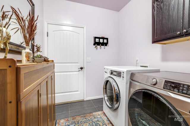 clothes washing area featuring cabinets, dark tile patterned flooring, and independent washer and dryer