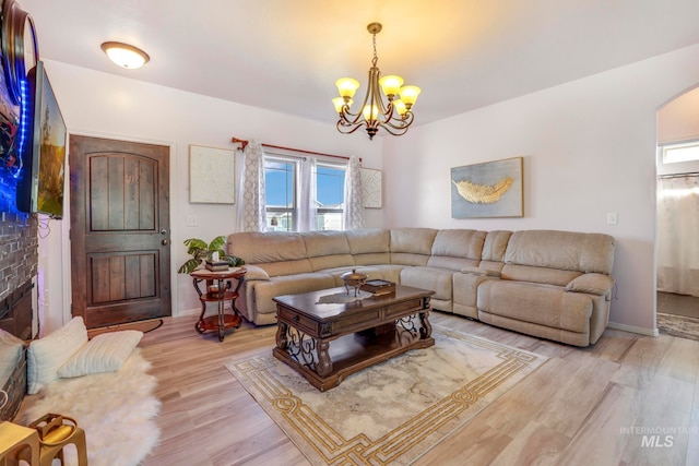 living room featuring light hardwood / wood-style floors, a fireplace, and a notable chandelier