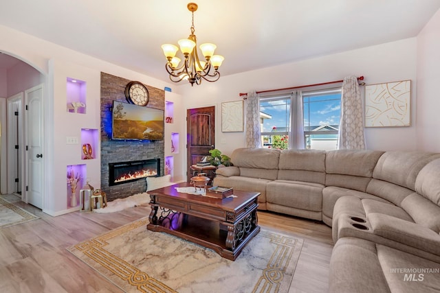 living room with light wood-type flooring, a fireplace, and a notable chandelier