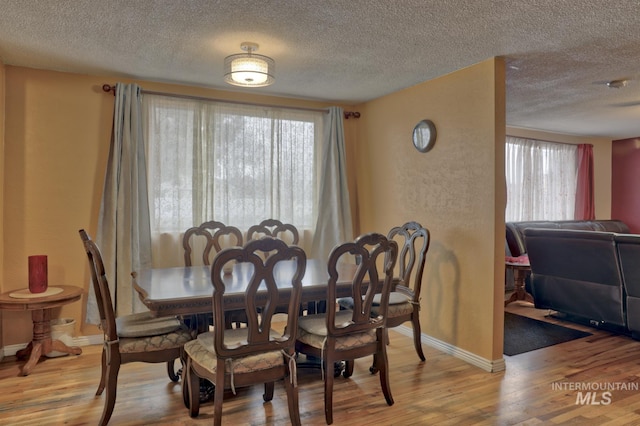 dining area with a textured ceiling and light hardwood / wood-style flooring