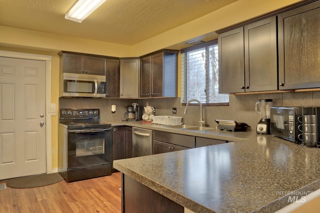 kitchen featuring backsplash, black appliances, sink, light hardwood / wood-style flooring, and dark brown cabinetry