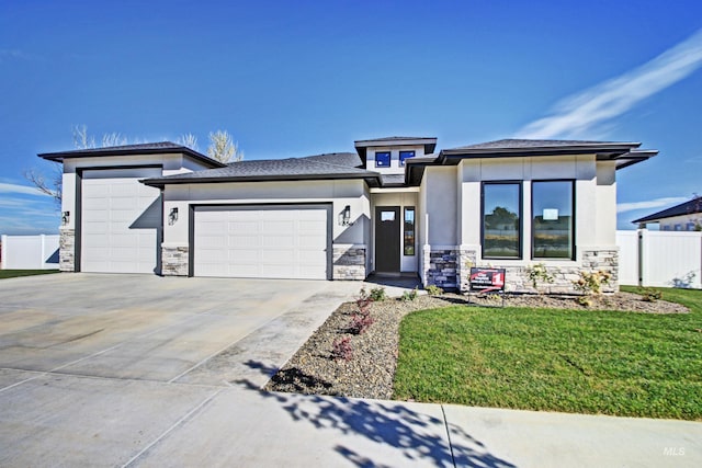 prairie-style house featuring a garage, fence, stone siding, driveway, and stucco siding