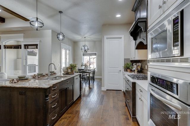 kitchen featuring appliances with stainless steel finishes, decorative backsplash, sink, pendant lighting, and dark wood-type flooring