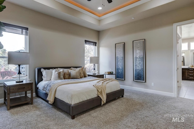 carpeted bedroom with ceiling fan, ensuite bathroom, a tray ceiling, and crown molding