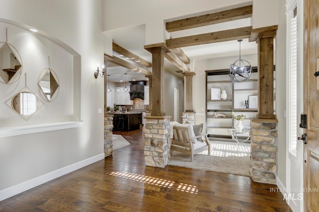 interior space with a chandelier, dark hardwood / wood-style floors, and ornate columns