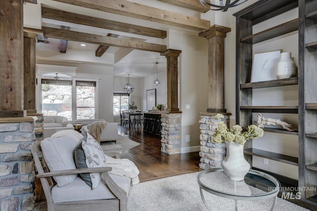 living room featuring decorative columns, beamed ceiling, and dark hardwood / wood-style flooring