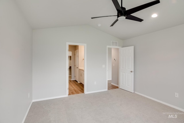 unfurnished bedroom featuring ceiling fan, vaulted ceiling, light colored carpet, and ensuite bath