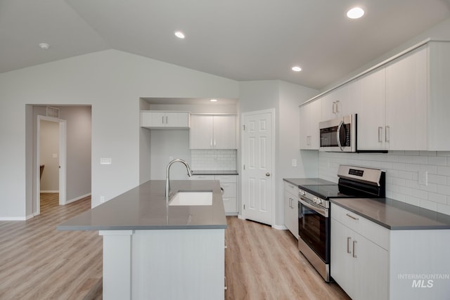 kitchen with lofted ceiling, sink, appliances with stainless steel finishes, backsplash, and white cabinets