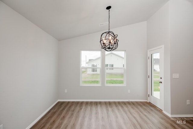 unfurnished dining area with lofted ceiling, a notable chandelier, and light hardwood / wood-style flooring