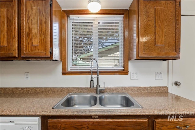 kitchen with a sink, dishwasher, brown cabinetry, and light countertops