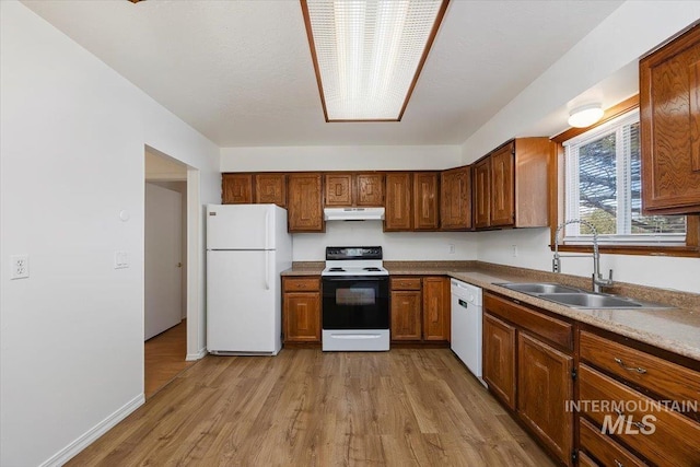 kitchen with white appliances, baseboards, a sink, under cabinet range hood, and light wood-type flooring