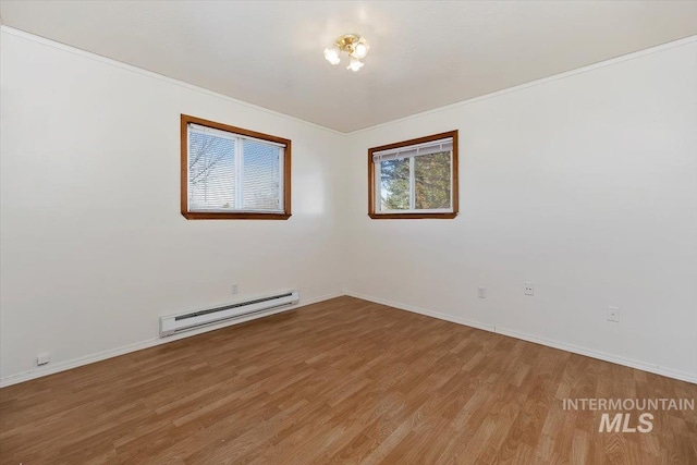 empty room with light wood finished floors, ornamental molding, baseboards, and a baseboard radiator