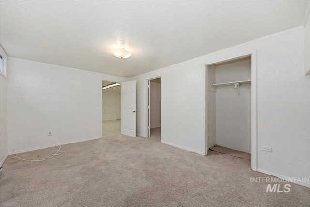 unfurnished bedroom with baseboards, ornamental molding, a closet, a textured ceiling, and light colored carpet