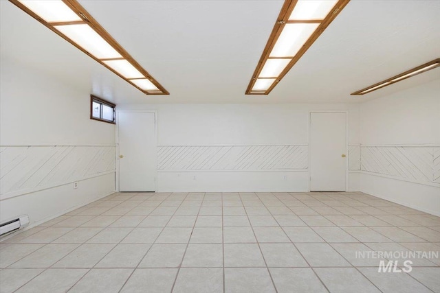 spare room with light tile patterned floors, wainscoting, and a baseboard heating unit