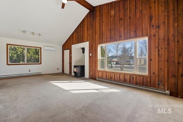 unfurnished living room with a wood stove, baseboard heating, wood walls, and carpet flooring