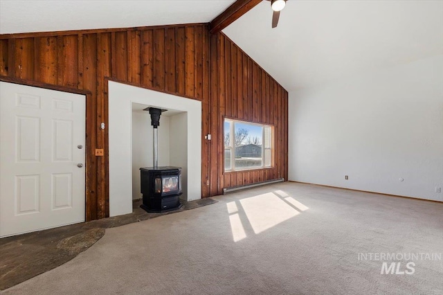 unfurnished living room with a baseboard heating unit, beam ceiling, carpet flooring, and wood walls