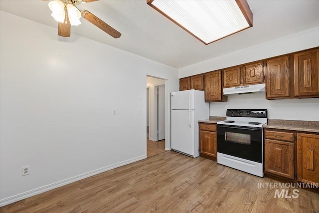 kitchen featuring brown cabinetry, light wood-style flooring, freestanding refrigerator, range with electric cooktop, and under cabinet range hood