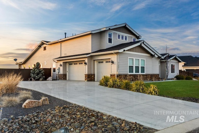 craftsman house with board and batten siding, fence, concrete driveway, stone siding, and an attached garage