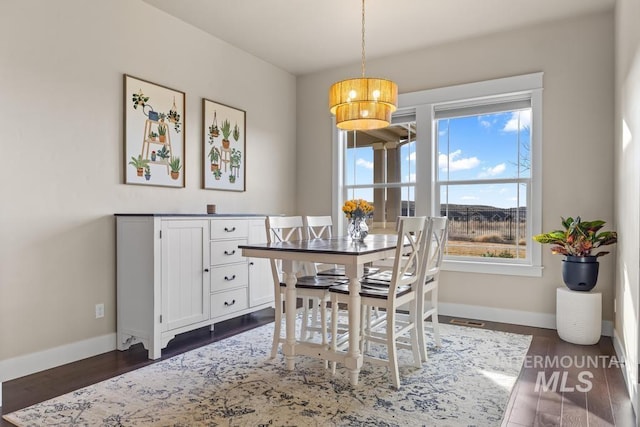 dining space featuring a chandelier, baseboards, and dark wood-style flooring