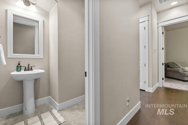 bathroom with visible vents, wood finished floors, baseboards, and a sink