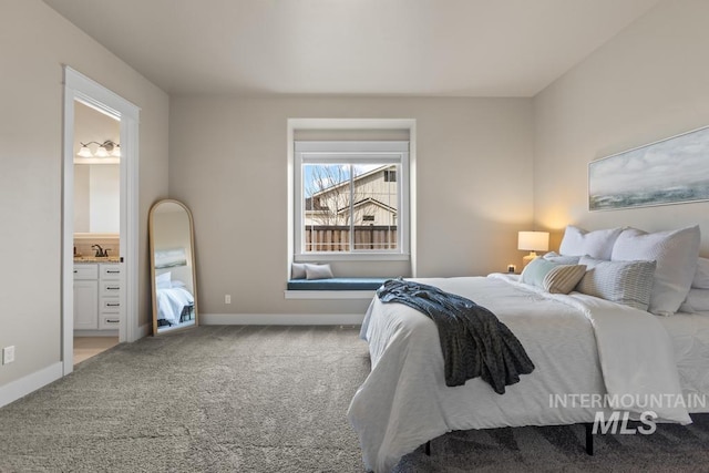 carpeted bedroom featuring ensuite bathroom, baseboards, and a sink