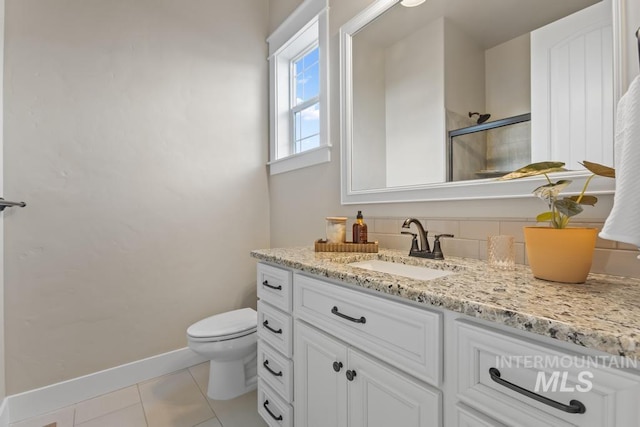 full bathroom featuring vanity, baseboards, a stall shower, tile patterned floors, and toilet