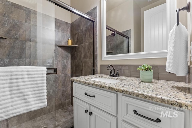 bathroom with a tile shower and vanity