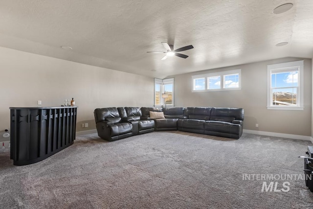 living room with baseboards, a textured ceiling, ceiling fan, and carpet flooring