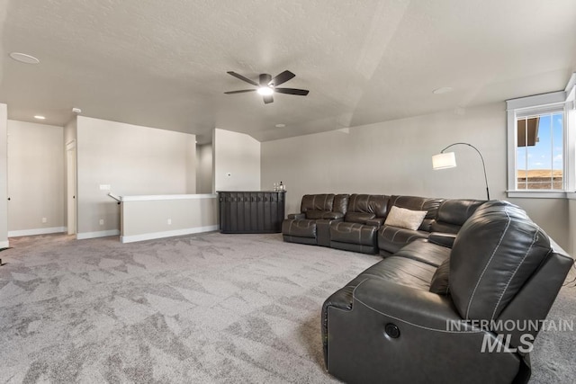 carpeted living room featuring baseboards, a textured ceiling, and ceiling fan