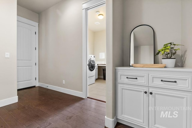 hallway featuring washer / dryer, baseboards, and dark wood-style flooring