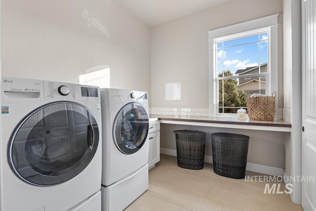 laundry area with light tile patterned floors, cabinet space, and washer and clothes dryer