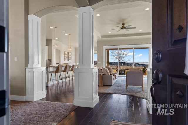 entryway featuring arched walkways, dark wood finished floors, a ceiling fan, and decorative columns