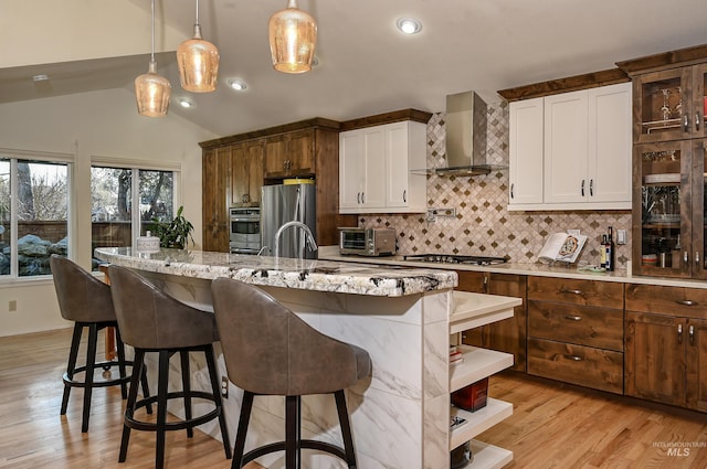 kitchen with wall chimney exhaust hood, freestanding refrigerator, gas stovetop, vaulted ceiling, and tasteful backsplash