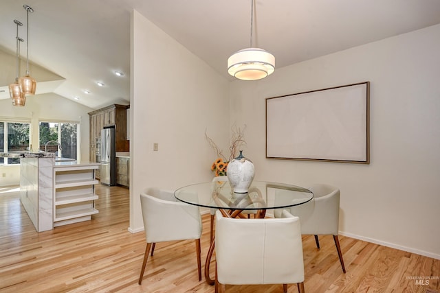 dining space featuring light wood-style flooring, vaulted ceiling, and baseboards