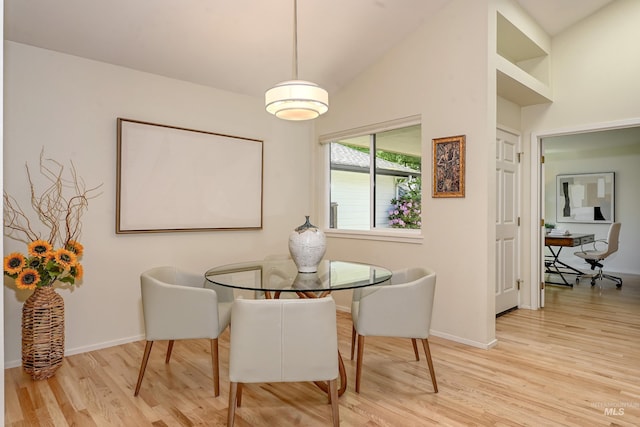 dining area with wood finished floors, baseboards, and high vaulted ceiling
