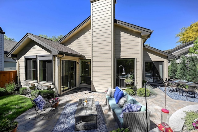 back of house with an outdoor living space, a patio, a chimney, and fence