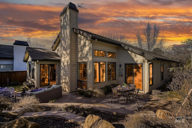 rear view of property featuring a patio area, outdoor lounge area, a chimney, and fence