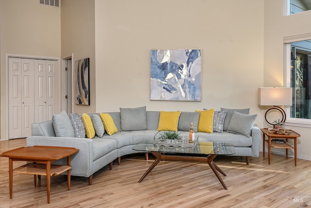 living area featuring a towering ceiling, wood finished floors, and baseboards