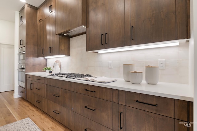 24910 Ardmore Ct, Caldwell, ID 83607 - kitchen featuring decorative backsplash, light wood-type flooring, light countertops, and under cabinet range hood