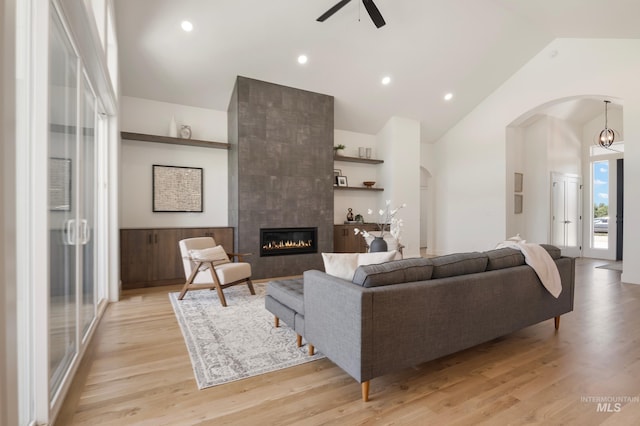 24910 Ardmore Ct, Caldwell, ID 83607 - living room featuring arched walkways, a ceiling fan, light wood-style floors, a fireplace, and high vaulted ceiling